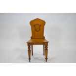 A Victorian oak hall chair with a shaped solid back, and a blank shield to the centre,