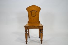 A Victorian oak hall chair with a shaped solid back, and a blank shield to the centre,