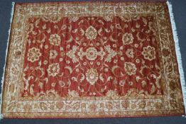 A machine woven Zeigler style carpet with scrolling flowers on a red ground