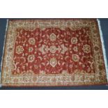 A machine woven Zeigler style carpet with scrolling flowers on a red ground