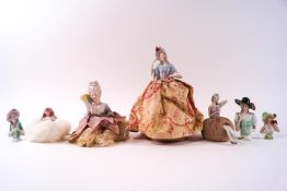 A group of seven porcelain half doll pin cushion ladies,