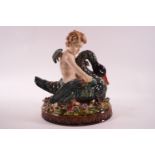 A 19th century Majolica figure of a putti riding a swan on oval flower encrusted base,