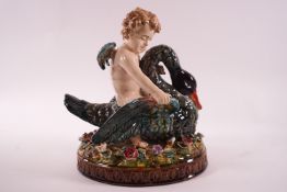 A 19th century Majolica figure of a putti riding a swan on oval flower encrusted base,