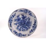 A Delft charger decorated with a central floral spray in cobalt,