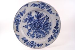 A Delft charger decorated with a central floral spray in cobalt,