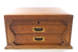 A fitted oak canteen cabinet of rectangular form with rising lid over two drawers,