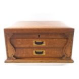 A fitted oak canteen cabinet of rectangular form with rising lid over two drawers,