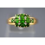 A yellow metal dress ring set with intense green peridot (untested) and single cut diamonds.