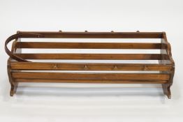 A walnut cradle, of semi-circular form with slat sides, set eight peg motifs and cut out handles,