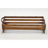 A walnut cradle, of semi-circular form with slat sides, set eight peg motifs and cut out handles,