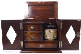 An oak smoker's cabinet with two lozenge glazed doors and lifting top,