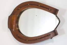 A wall mirror in an oak and brass studded horse shoe shaped frame,