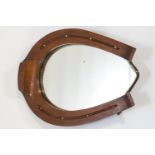 A wall mirror in an oak and brass studded horse shoe shaped frame,