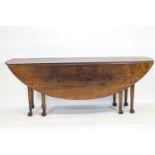 An oak wake dining table, in the early 18th century style, the planked oval top with two leaves,