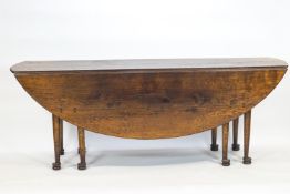 An oak wake dining table, in the early 18th century style, the planked oval top with two leaves,