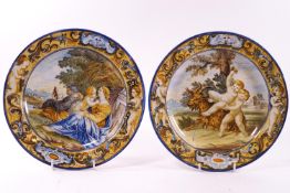 A pair of polychrome decorated Majolica plates, both decorated with borders of foliate scrolls,