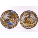 A pair of polychrome decorated Majolica plates, both decorated with borders of foliate scrolls,