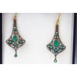 A yellow and white metal pair of drop earrings set with emeralds and single cut diamonds.