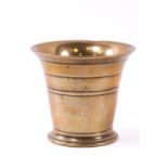 A brass mortar of traditional bell form with turned band decoration,