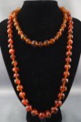A single strand of off round amber beads together with a single strand of faceted amber beads