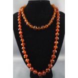 A single strand of off round amber beads together with a single strand of faceted amber beads