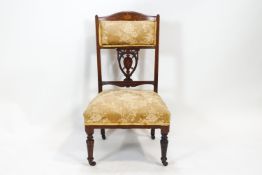 An Edwardian walnut salon/nursing chair with shaped back rail inlaid with a central patera