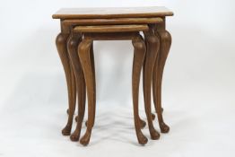 A nest of three carved hard wood tables with shaped rectangular tops raised on cabriole legs