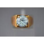 A yellow metal single stone ring set with a round faceted cut synthetic blue spinel. Size N.