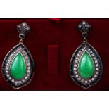 A yellow and white metal pair of drop earrings each set with a pear shape cabochon jadeite...