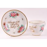 A large 19th century bone china cup and saucer, decorated with floral sprays and a gilt motto,