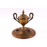 A brass inkwell in the form of a two handled campana shaped urn on a domed base