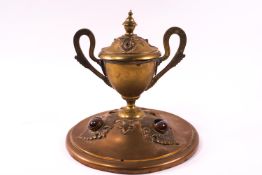 A brass inkwell in the form of a two handled campana shaped urn on a domed base