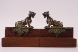 A pair of decorative bronze lion finial figures on mahogany bases,