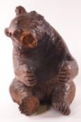 A carved Black forest style bear in seated position with paws out stretched,