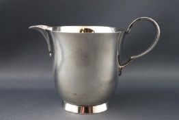 A cream jug of inverted bell form with curved handle and flared foot, London 1953, 7cm high,