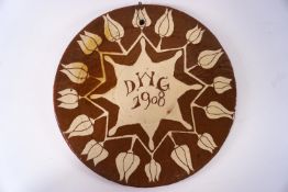 An early 20th century slip ware wall plaque, inscribed with the initials D.W.G