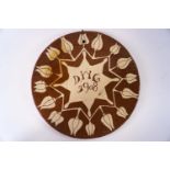 An early 20th century slip ware wall plaque, inscribed with the initials D.W.G