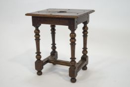 An oak stool, the top pierced with a heart on turned legs linked by stretchers,
