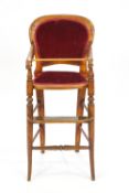 A child's beech wood and upholstered high chair with shaped back over splayed arms
