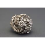 A white metal abstract cluster ring set with a principal round brilliant cut diamond ....