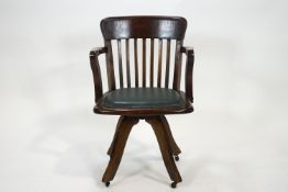 An oak revolving office chair on four splayed legs with casters