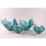 Four glass handkerchief bowls decorated with white stripes on blue ground,