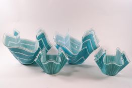 Four glass handkerchief bowls decorated with white stripes on blue ground,