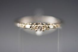 A white metal ring set with round brilliant and baguette cut diamonds.