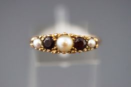 A yellow metal half hoop ring set with garnets and pearls.