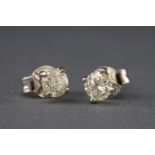 A white metal pair of single stone studs each set with a round brilliant cut diamonds.