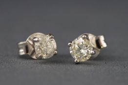 A white metal pair of single stone studs each set with a round brilliant cut diamonds.