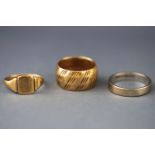 A selection of three yellow metal rings consisting of signet and wedding design.