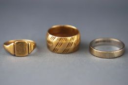 A selection of three yellow metal rings consisting of signet and wedding design.