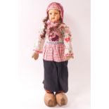 An early 20th century Dutch costume doll with papier-mâché face and wooden clogs,